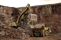 Huge tracked digger loading a six wheeled tipper truck.