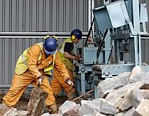 Busy workers in orange boiler suits and blue hard hats.