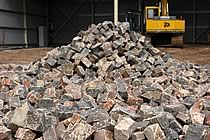 Mound of aggregate near a yellow digger.